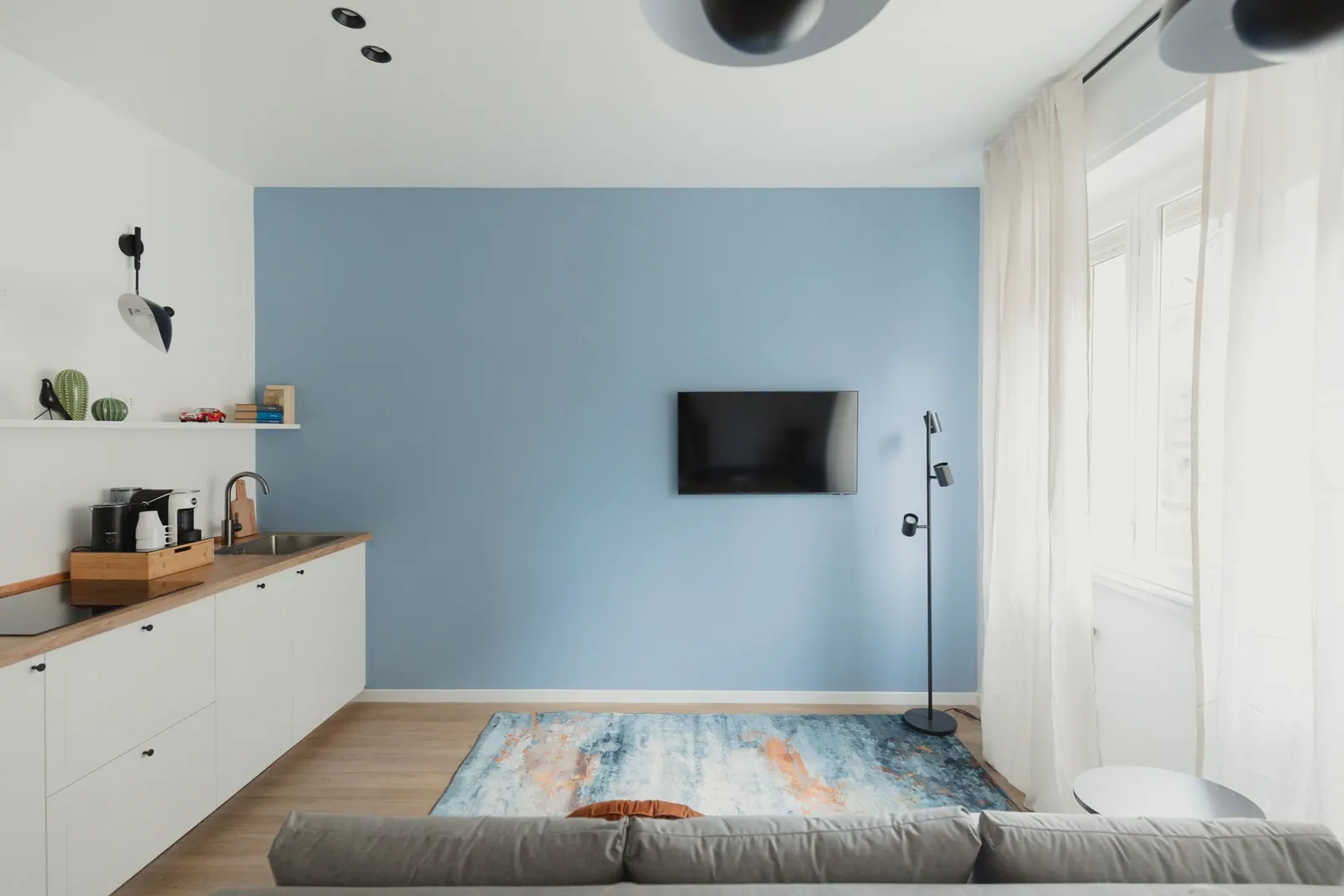 Bilo Blu: salón con pared azul, cocina y sofá cama
